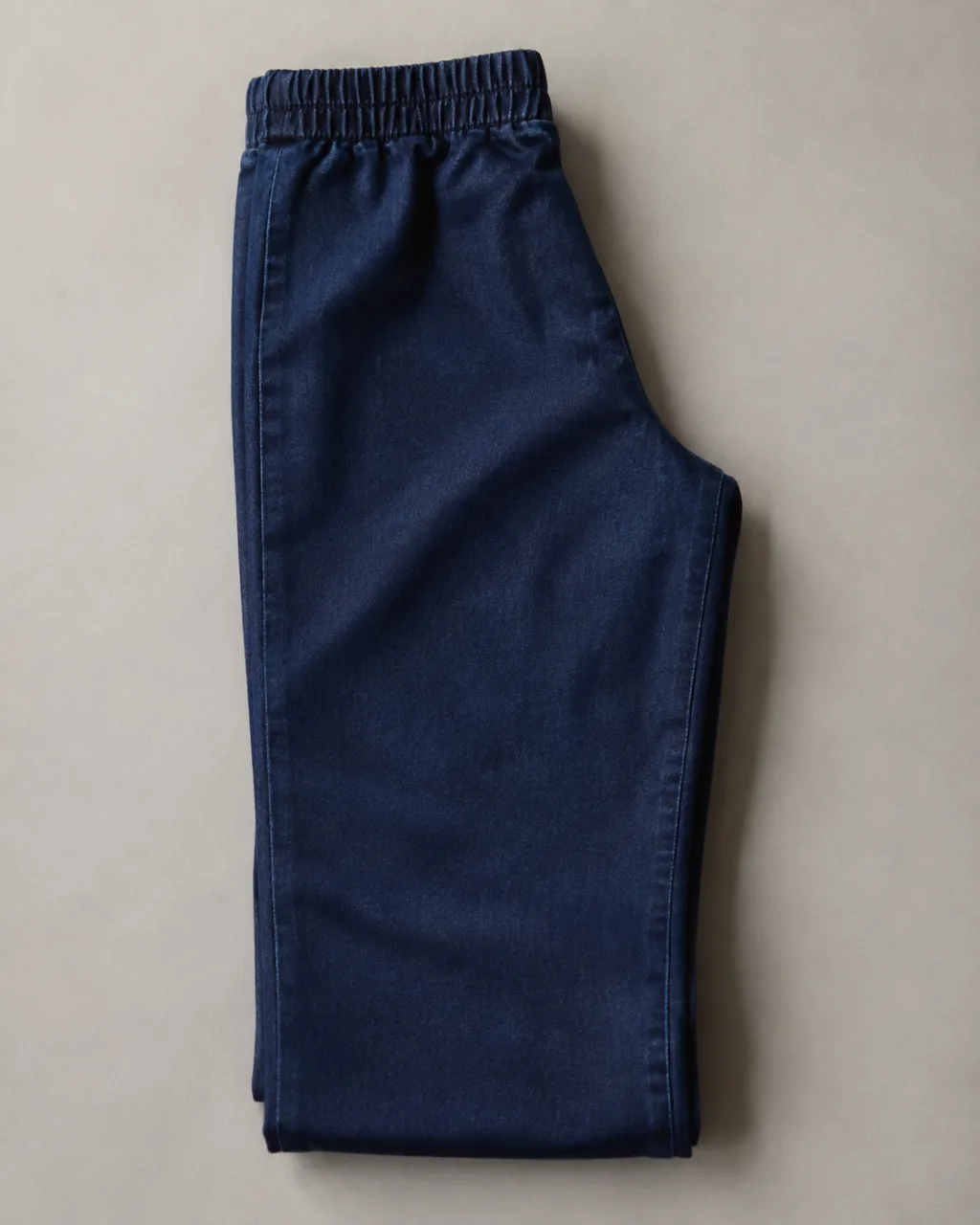 a pair of pull-on jeans folded in half lengthwise, side seam running down the frame with a high rise and a full elastic waistband , fabric: Stretch denim (cotton with elastomultiester and Lycra elastane)