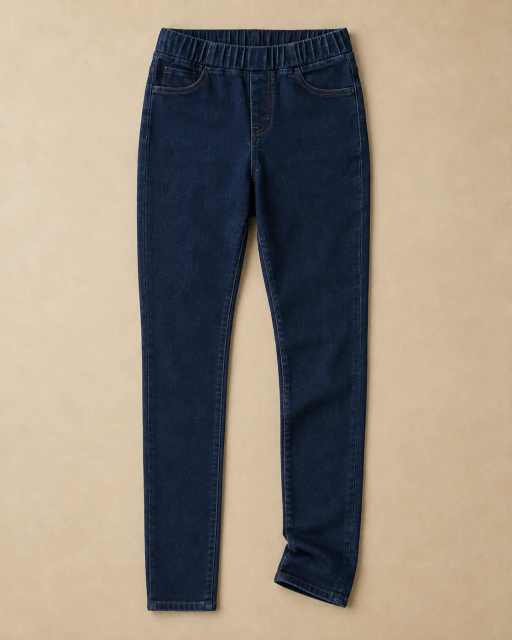 a pair of jeggings laid flat full length with a single soft fold at the hem with a mid rise and a full elastic waistband