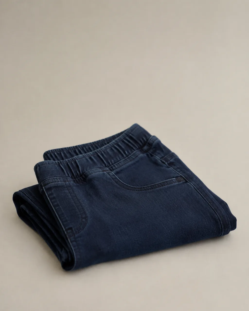 a pair of jeggings neatly folded into a square stack, waistband on top with a mid rise and a full elastic waistband