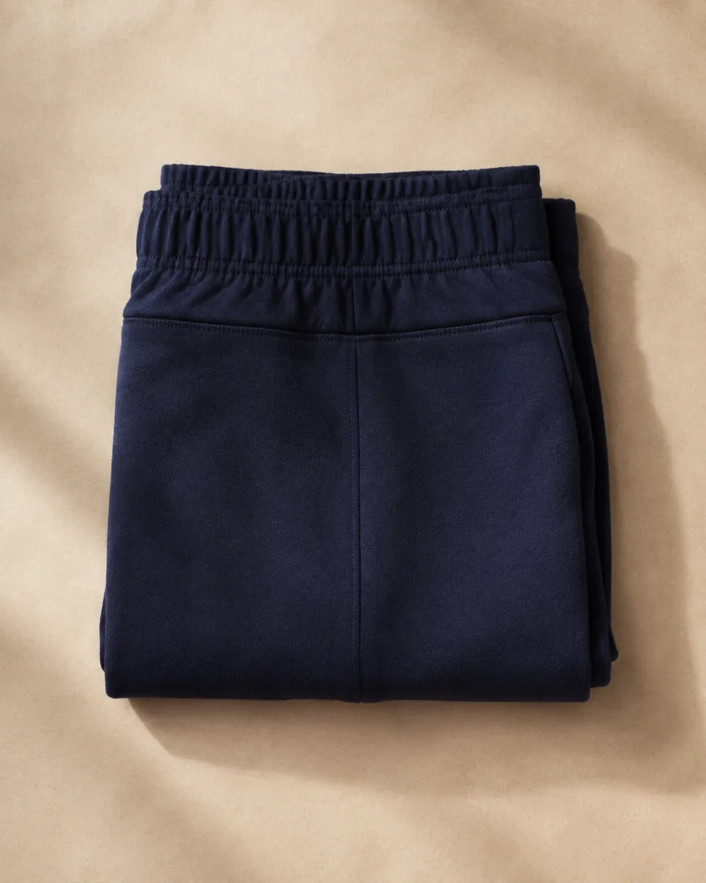a pair of ponte knit pants neatly folded into a square stack, waistband on top with a high rise and a full elastic waistband , fabric: Ponte knit