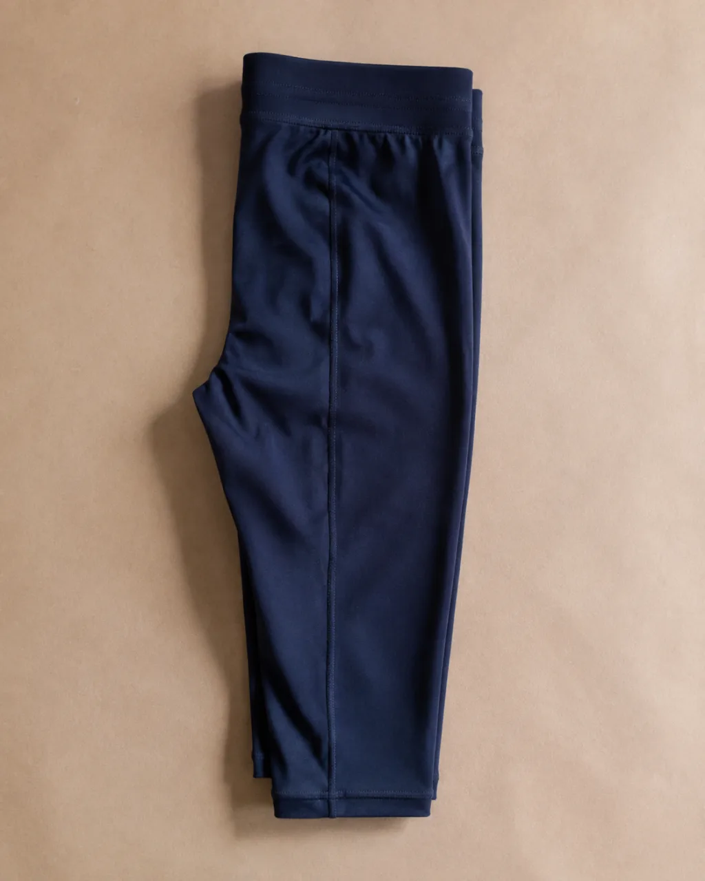 a pair of leggings folded in half lengthwise, side seam running down the frame with a full elastic waistband , fabric: Nylon/Lycra knit
